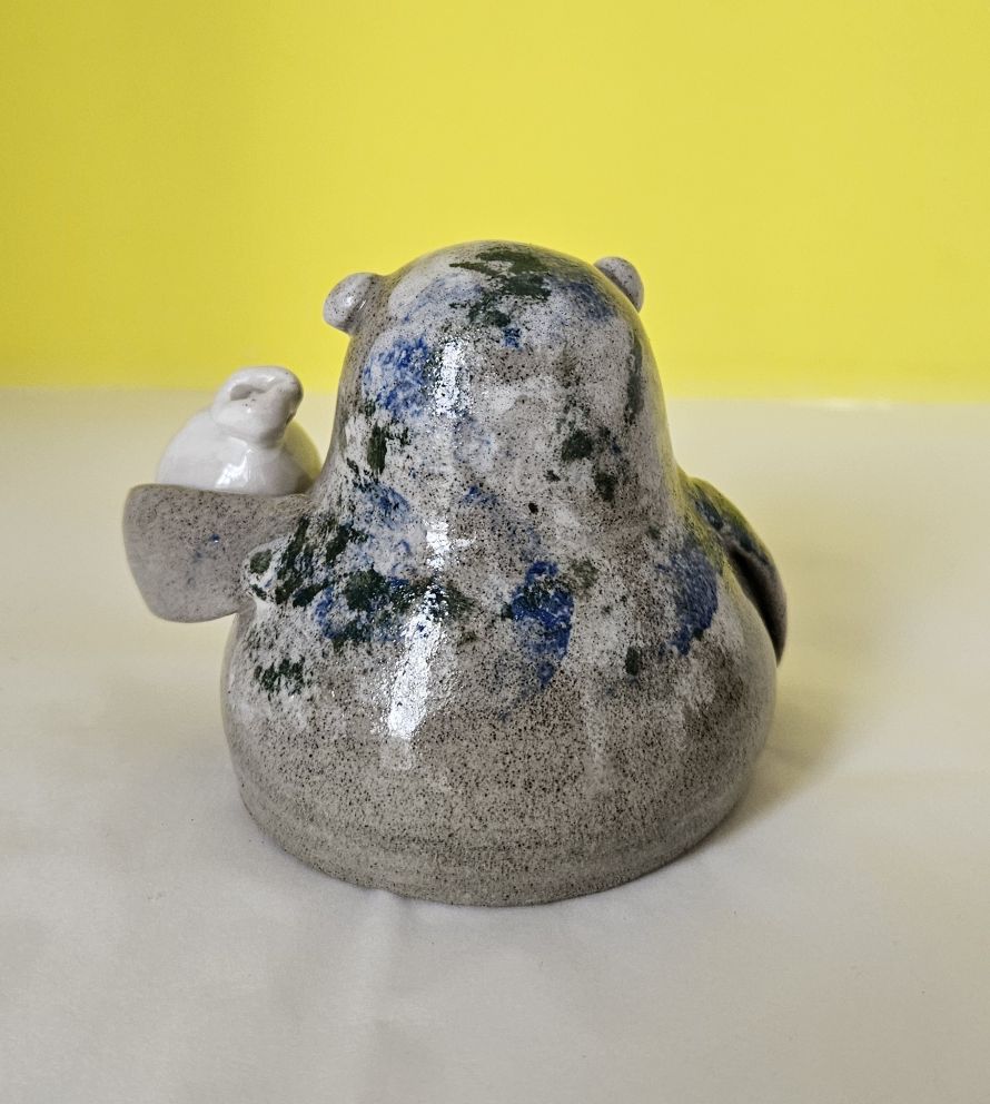 Ceramic pigeon ornament with bag of seed, seen from the back